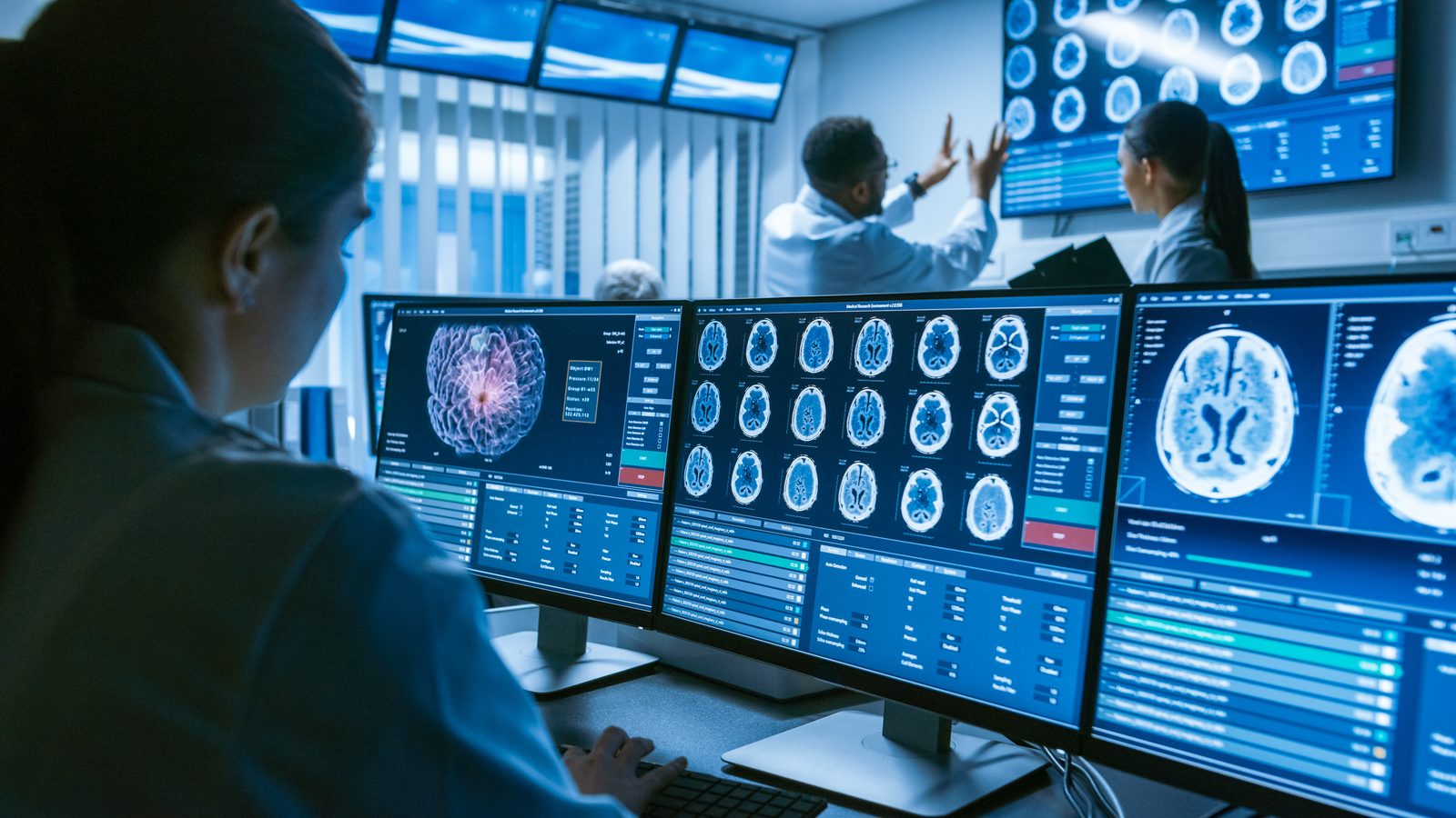Radiologists reviewing cross-sectional images on diagnostic monitors.